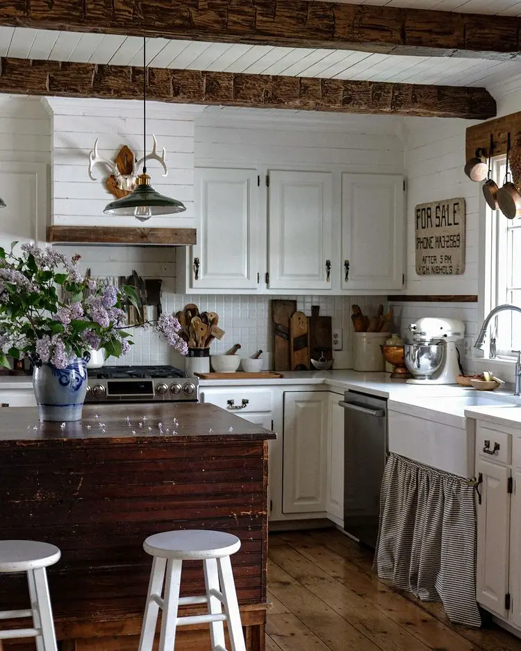 A cozy kitchen with wooden beams and white cabinets