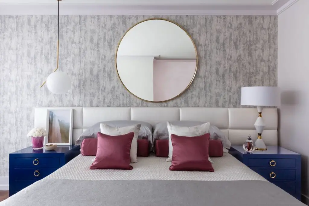 Gray bedroom with navy nightstands, berry accents