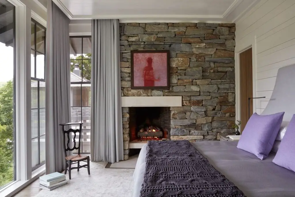 Bedroom featuring stone fireplace wall and balcony access