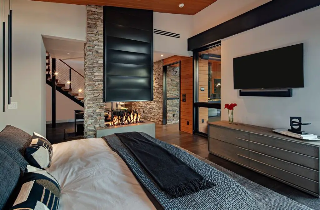 Modern bedroom with stone fireplace and loft-style design