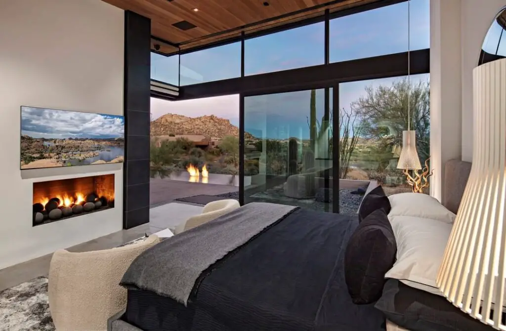 Luxury bedroom overlooking desert landscape with indoor fireplace
