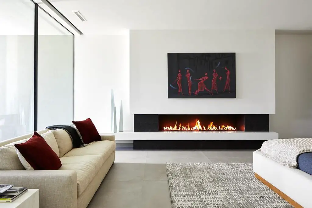 Modern bedroom featuring long fireplace and striking red artwork