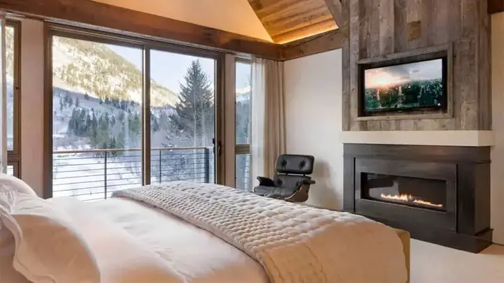 Luxurious bedroom with mountain views fireplace and balcony