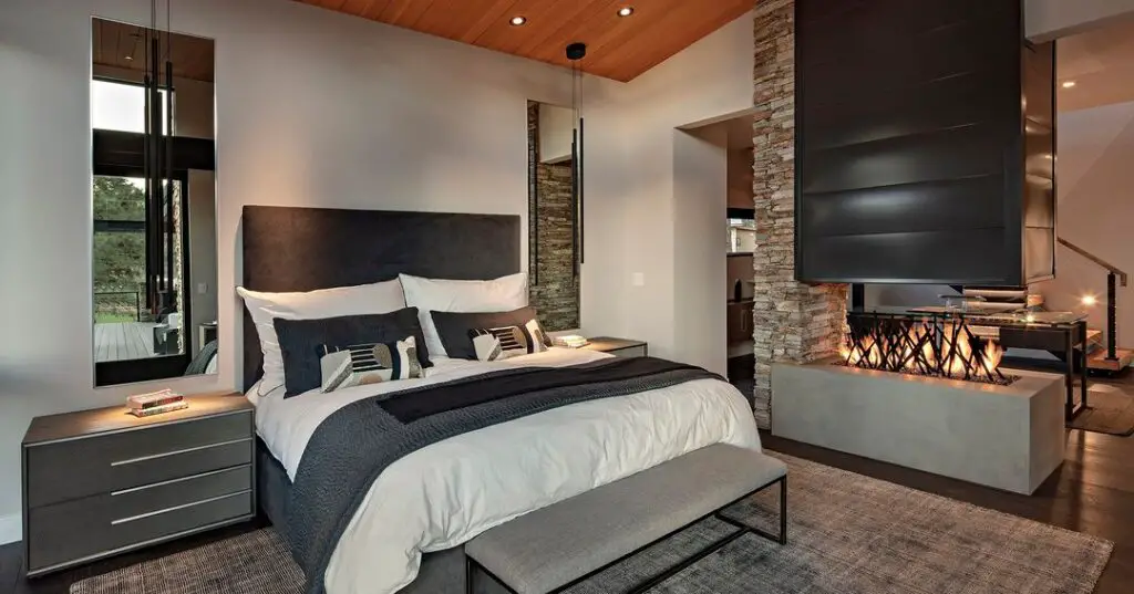 Stylish bedroom featuring stone fireplace column and wood ceiling
